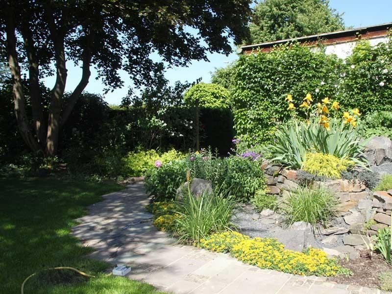 Ein Weg in einem Garten mit Blumen und Bäumen