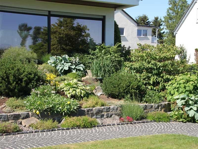 Ein üppiger grüner Garten mit einem weißen Haus im Hintergrund