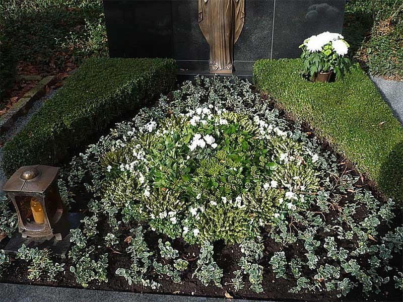 Ein Grab mit Blumen und einer Statue im Hintergrund