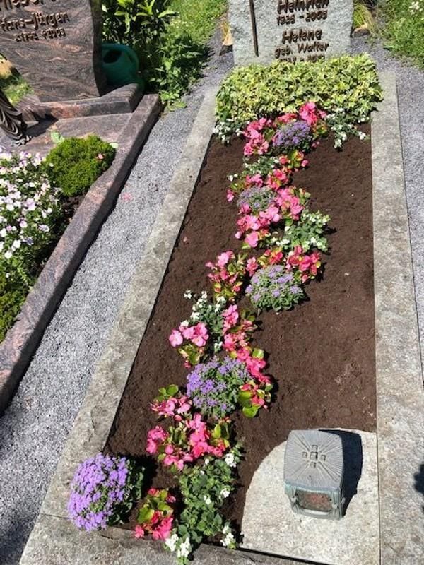 Ein Grab mit Blumen und einer Gießkanne darauf.