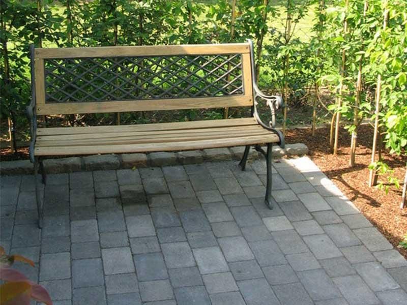 Eine Holzbank steht auf einer gemauerten Terrasse