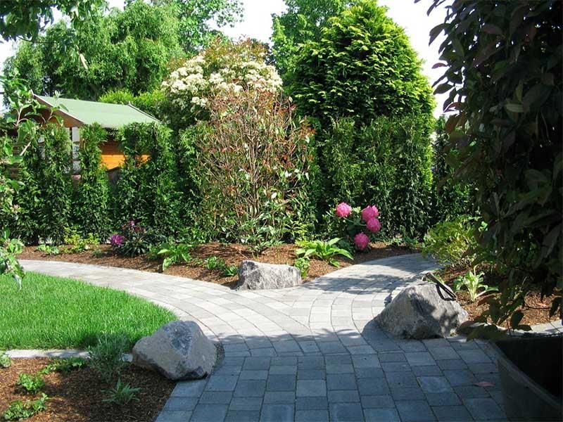 Ein gemauerter Gehweg, der zu einem Haus in einem Garten führt