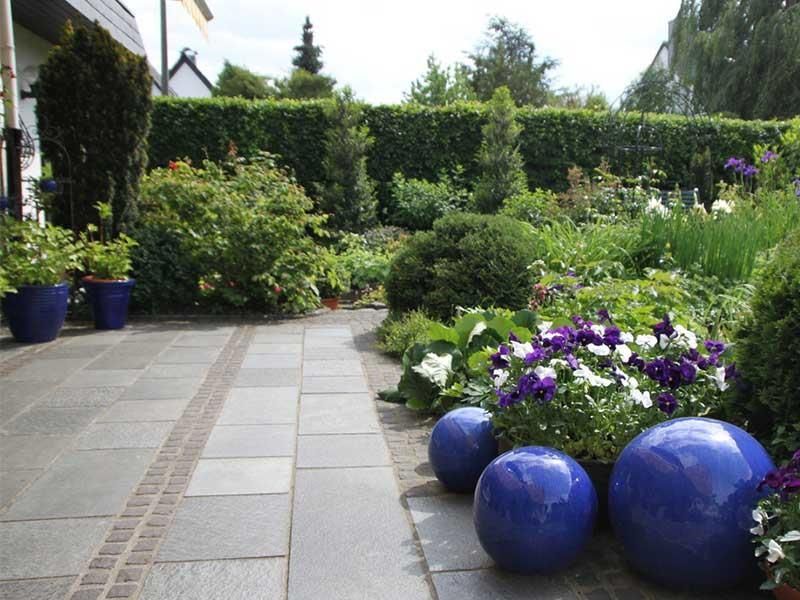 Ein Garten mit lila und weißen Blumen und blauen Kugeln