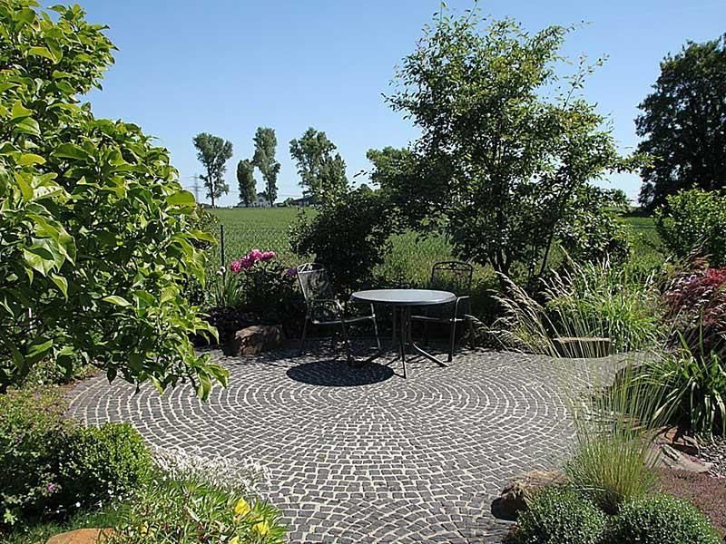 Eine Terrasse mit Tisch und Stühlen inmitten eines Gartens