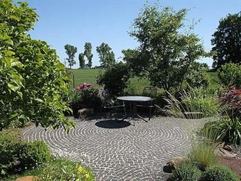Eine Terrasse mit Tisch und Stühlen inmitten eines Gartens.