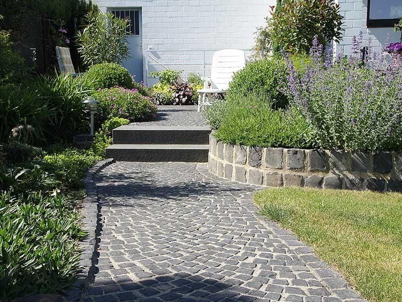 Ein Steinweg, der zu einem weißen Stuhl in einem Garten führt