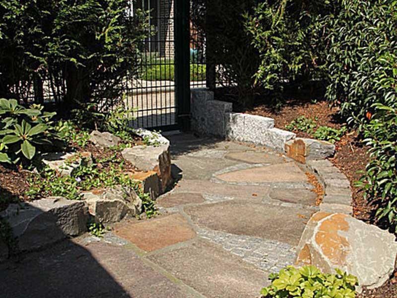 Ein Steinweg, der zu einem Tor in einem Garten führt