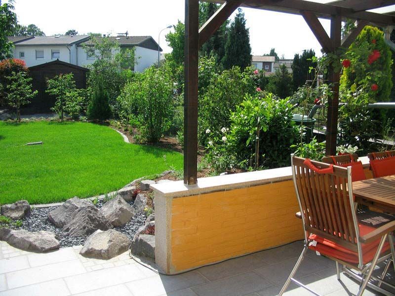 Eine Terrasse mit Tisch und Stühlen mit Blick auf einen üppigen grünen Garten