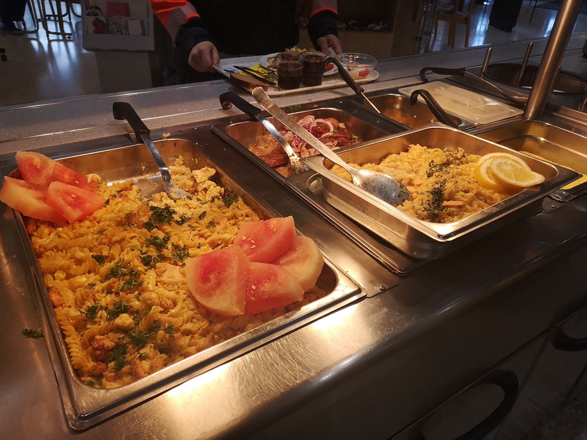 Ruokabuffet, jossa on erilaisia ​​annoksia metallitarjottimilla. Sisältää kuskusia, tomaattia ja sitruunalohkon.