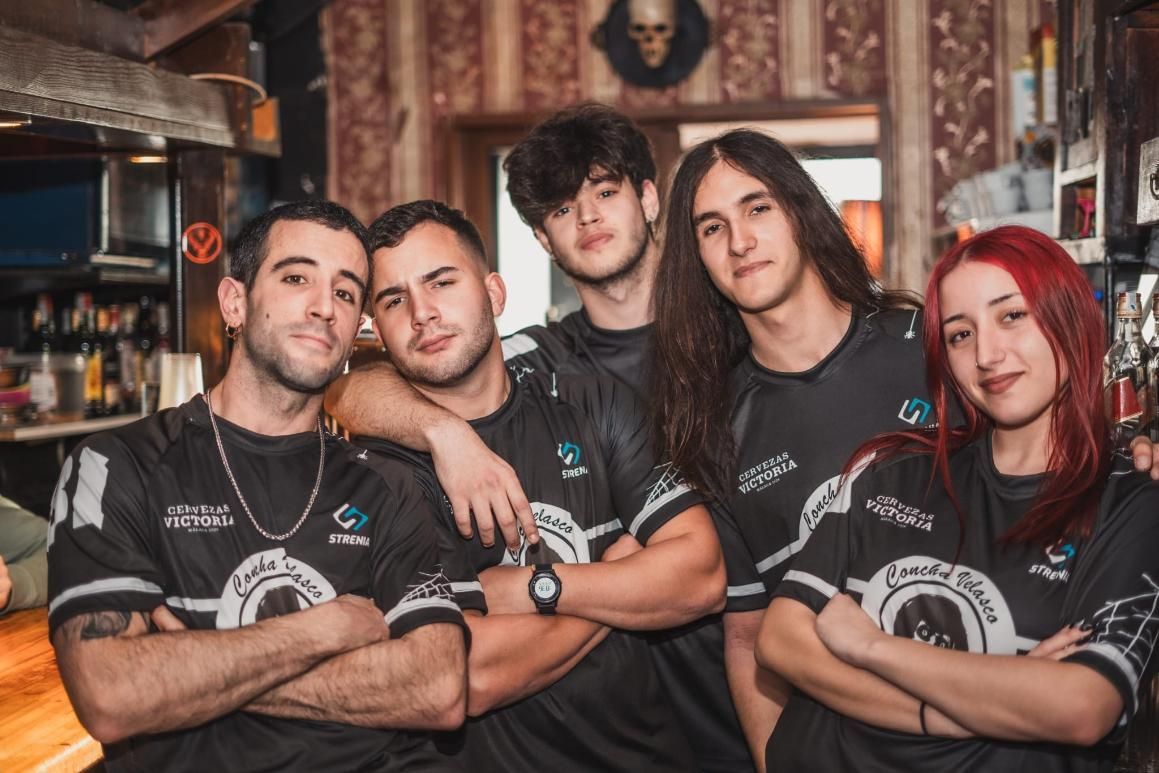 Cinco personas con camisetas negras posan en un bar. Cruzan los brazos y sonríen. Al fondo, un bar.