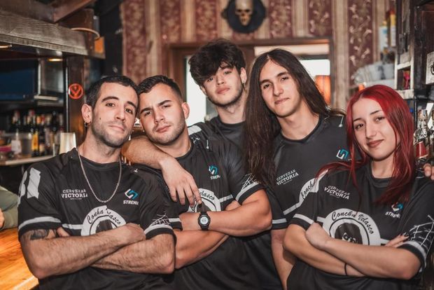 Cinco personas con camisetas negras posan en un bar. Cruzan los brazos y sonríen. Al fondo, un bar.