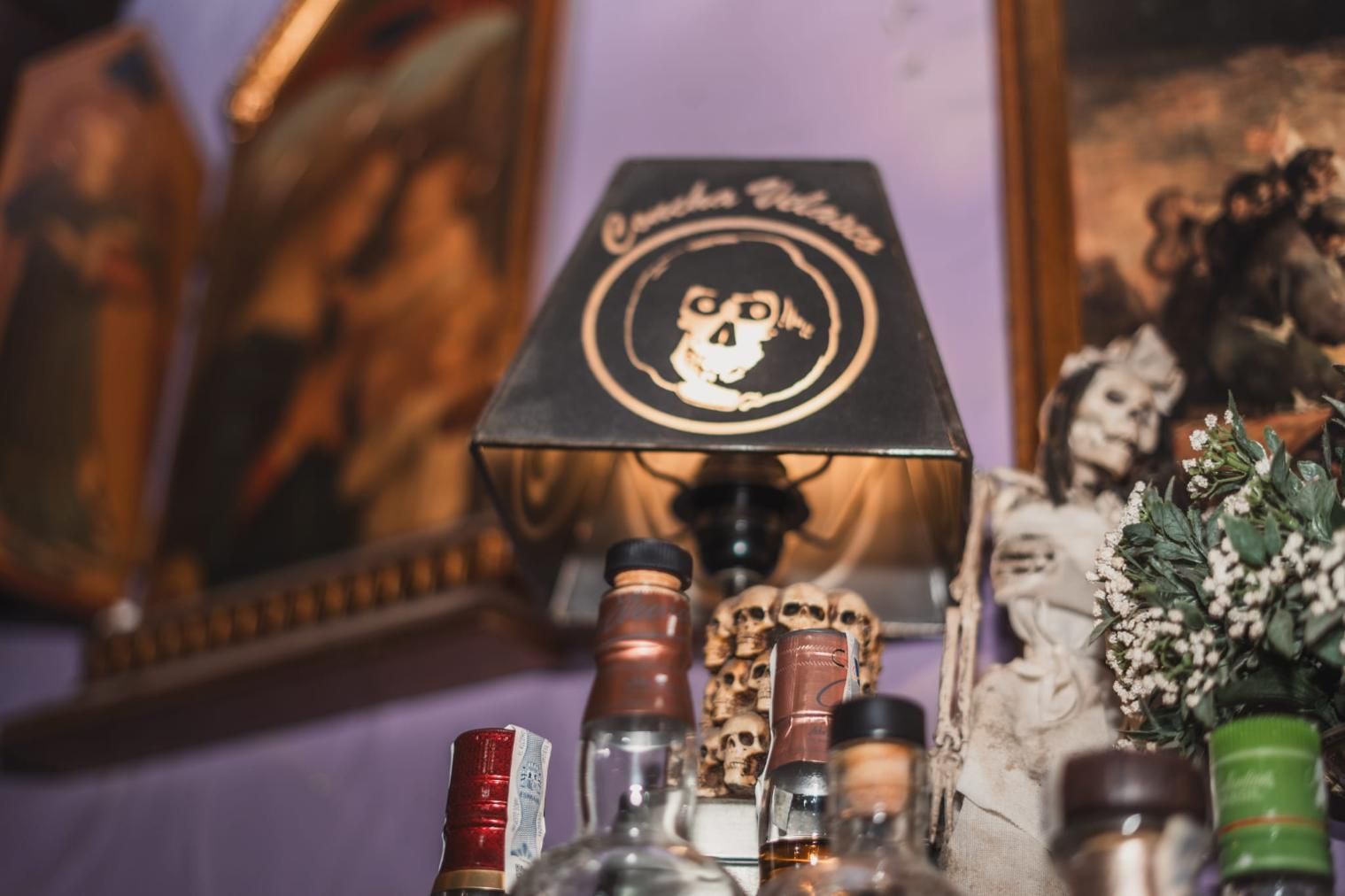Lámpara con diseño de calavera sobre botellas de licor.