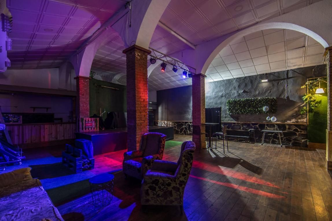 Espacio vacío para eventos con escenario, asientos y luces de colores.