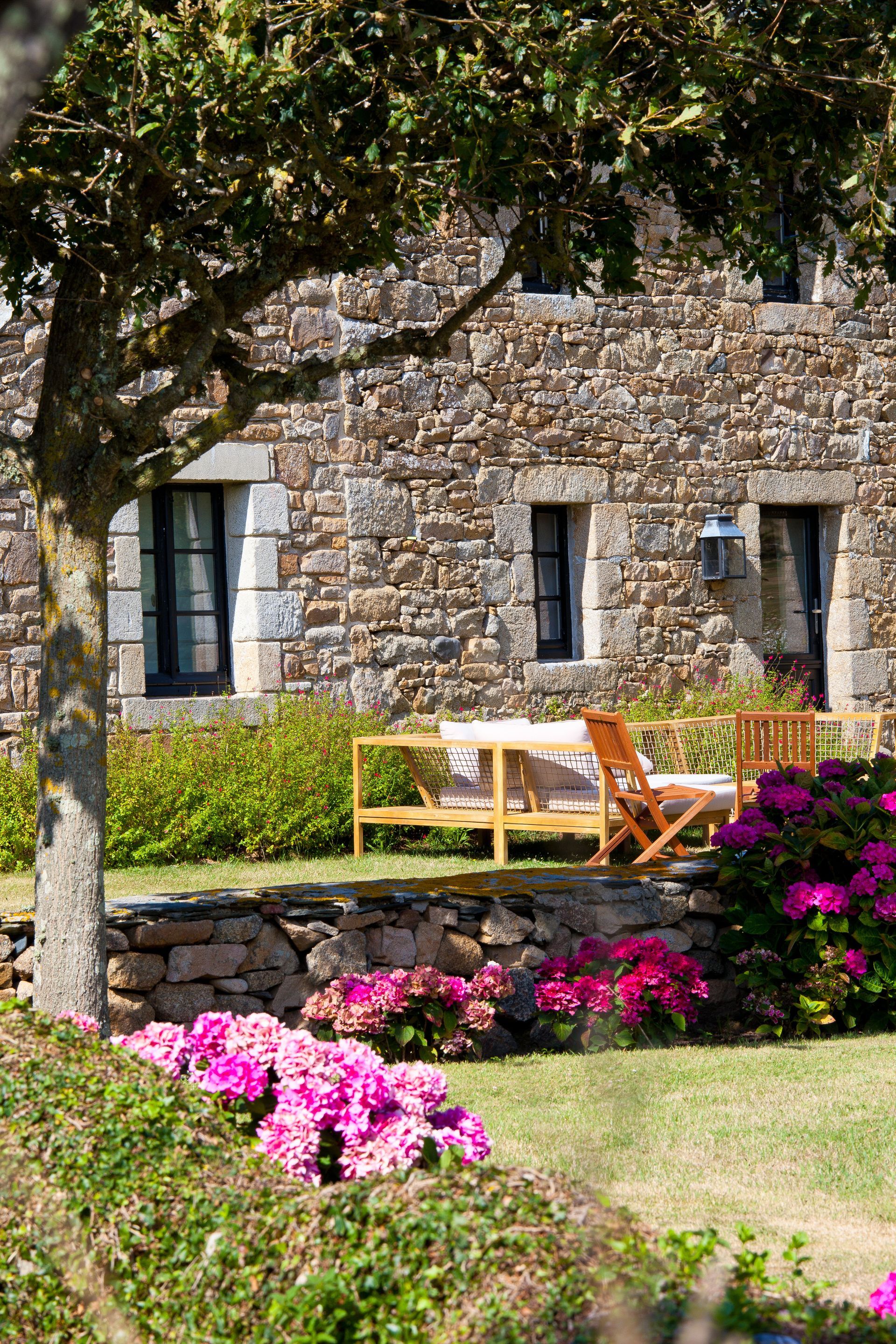 Un jardin paysagé avec maison en pierre bretonne.