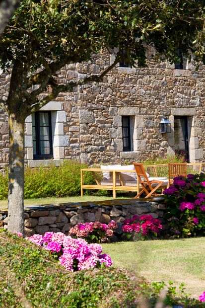 Un jardin paysagé avec maison en pierre bretonne.