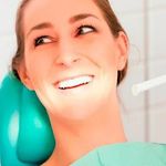 Una mujer sonríe mientras está sentada en una silla dental.
