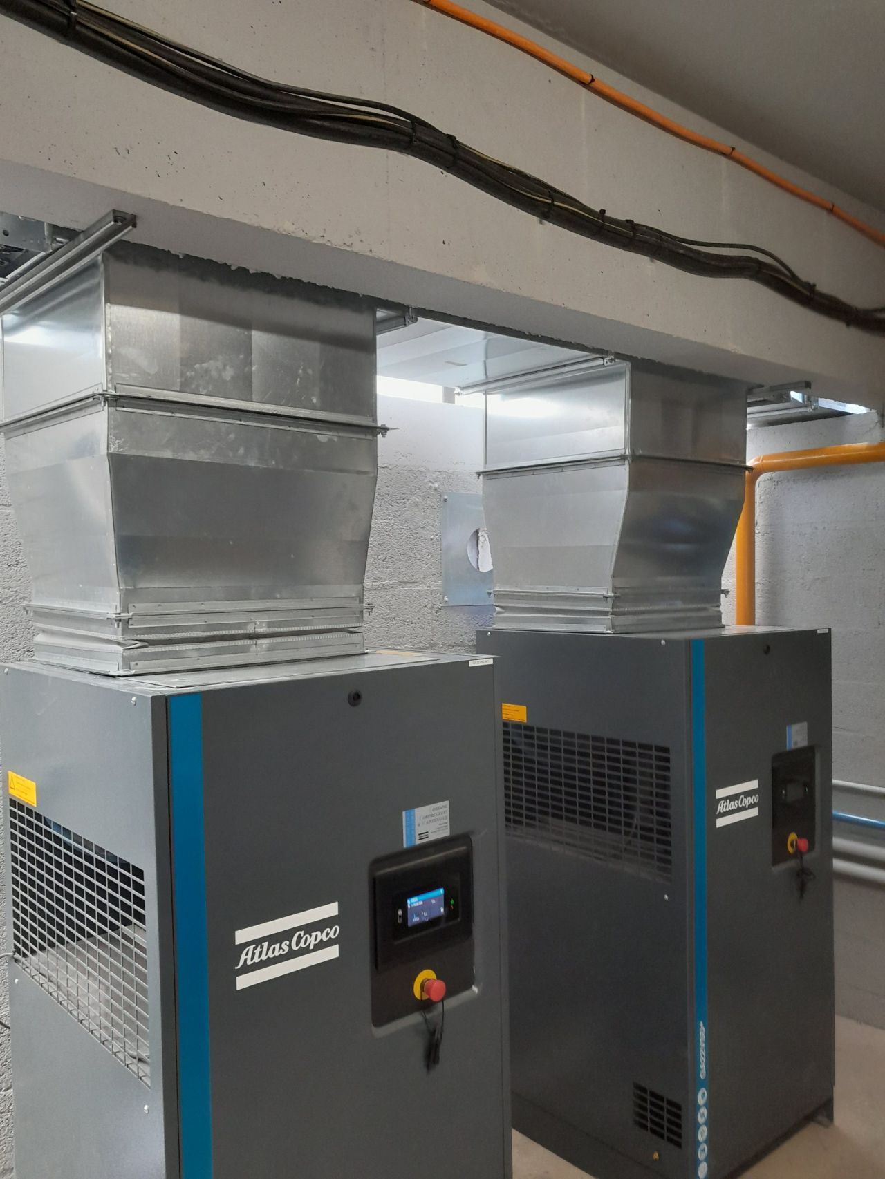 Deux compresseurs d'air reliés à des grosses bouches d'évacuation