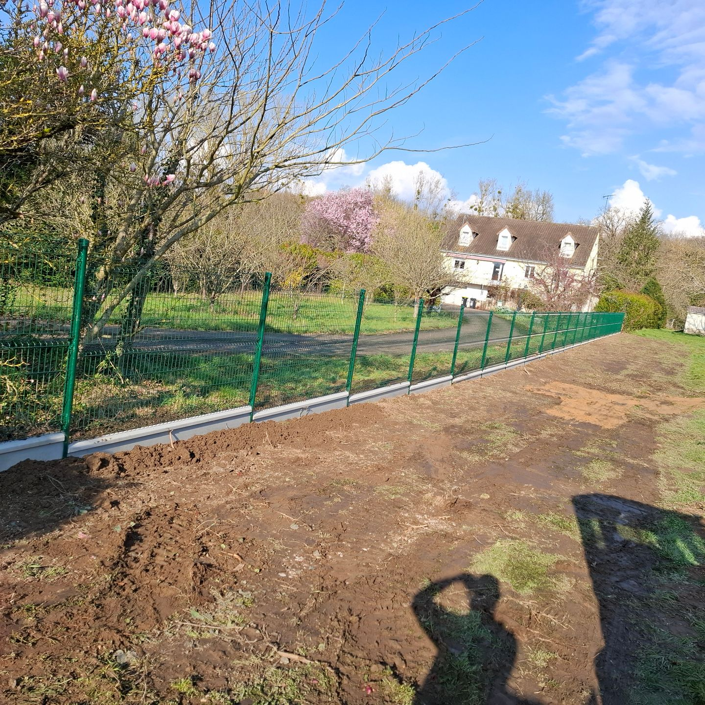 Une clôture verte bordant un espace vert.
