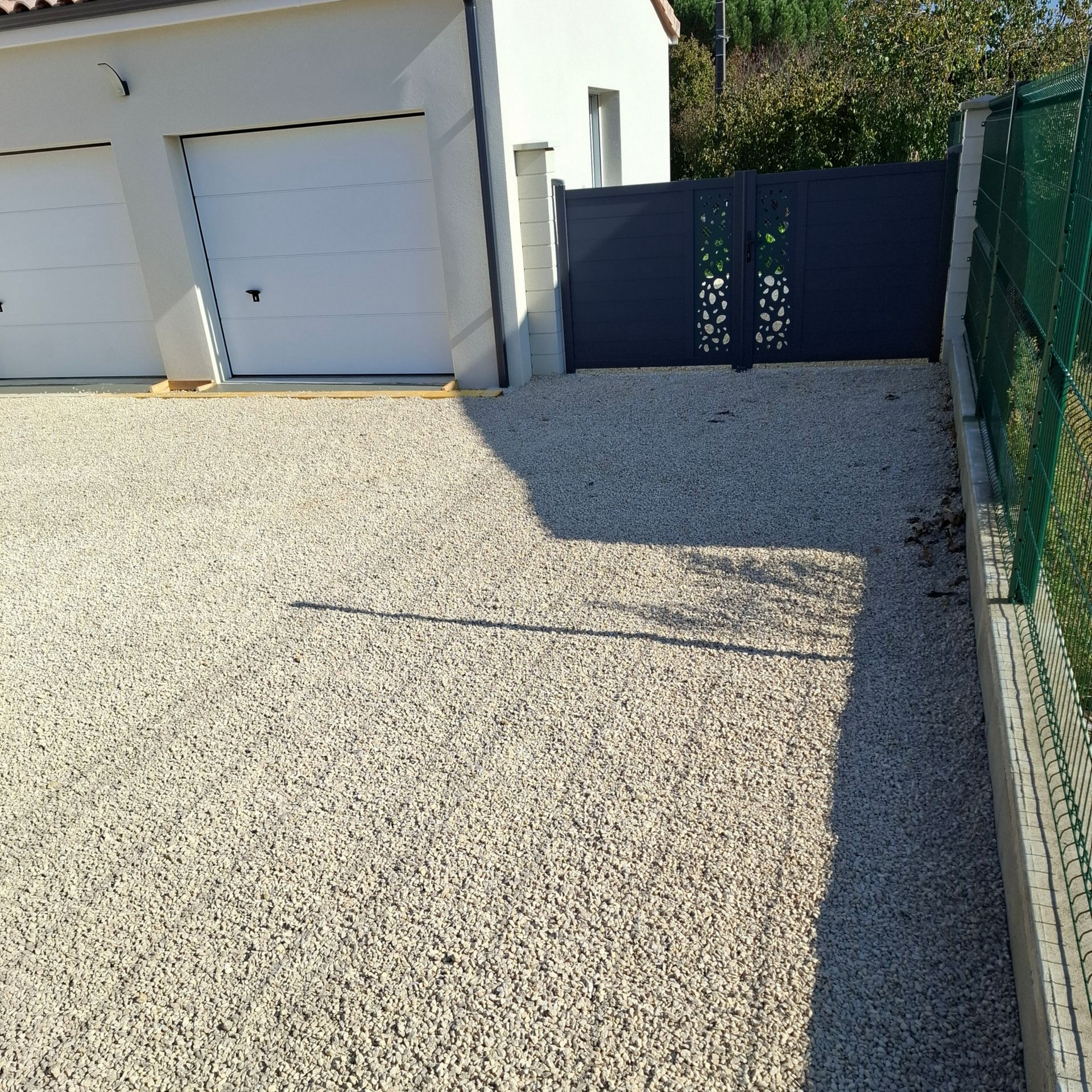 Une allée de gravier mène à un garage blanc.