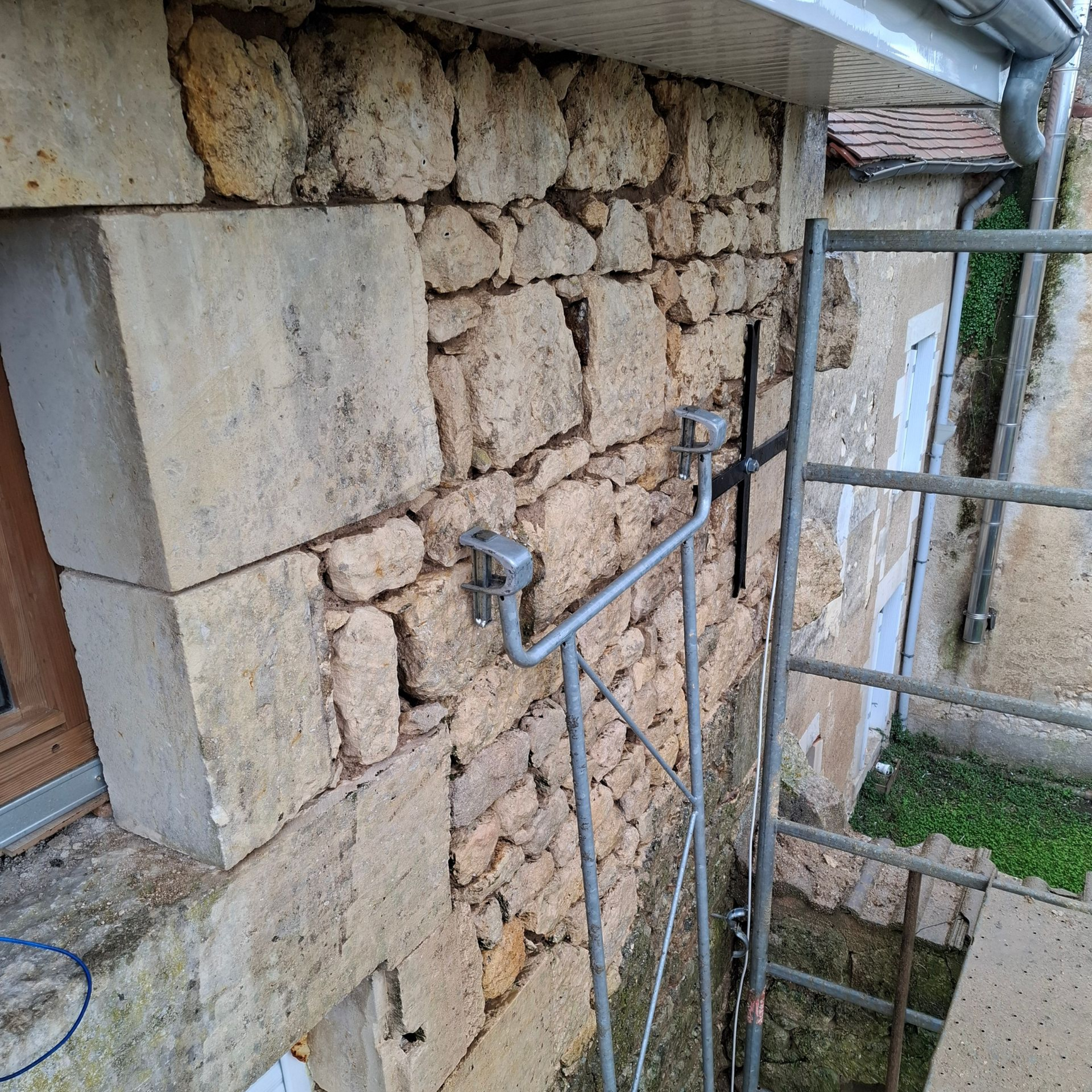 Mur en pierre d'un bâtiment avec des échafaudages à côté.