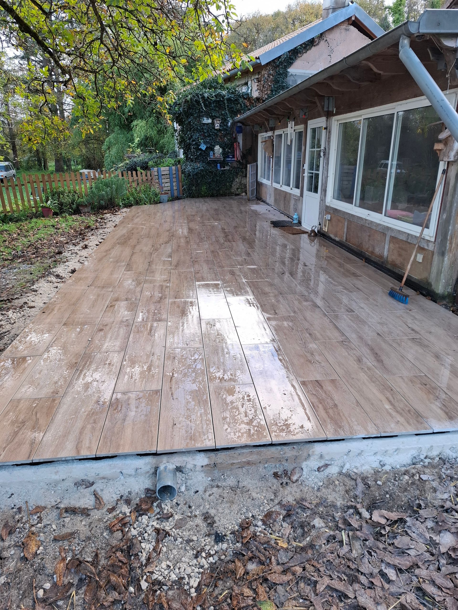 Terrasse carrelée et végétation.