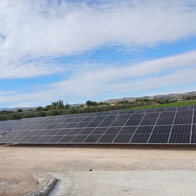 Una fila de paneles solares colocados sobre un campo de tierra.