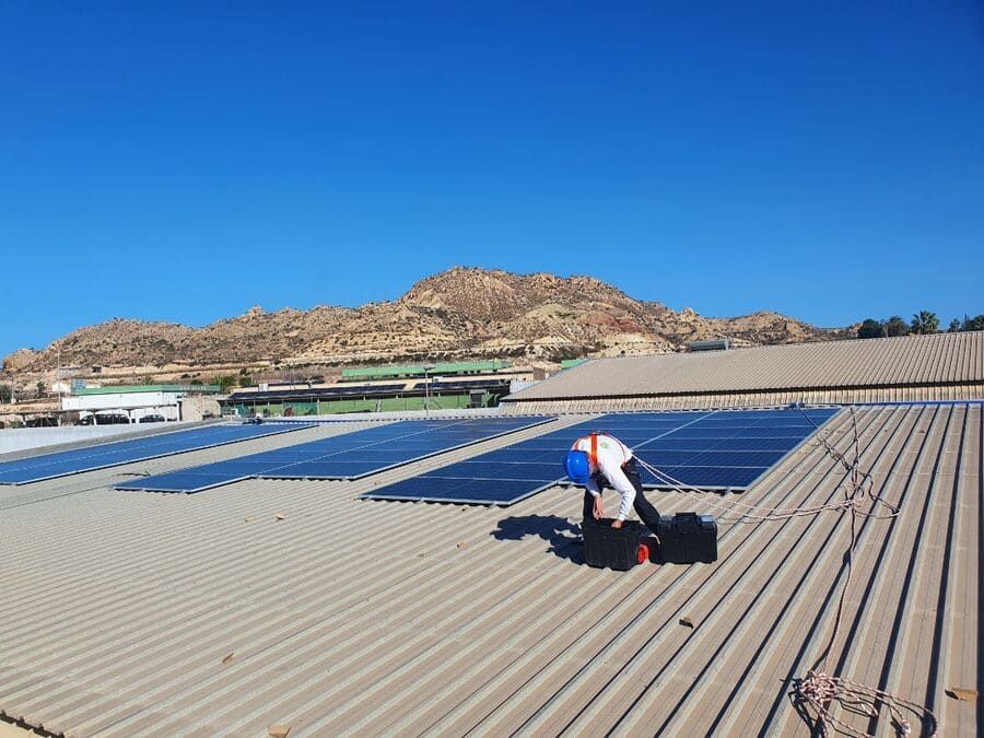 Un hombre está instalando paneles solares en el tejado de un edificio.