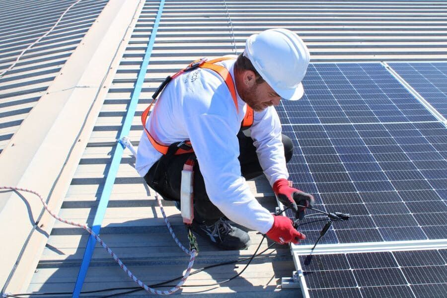 Un hombre está instalando paneles solares en un tejado.