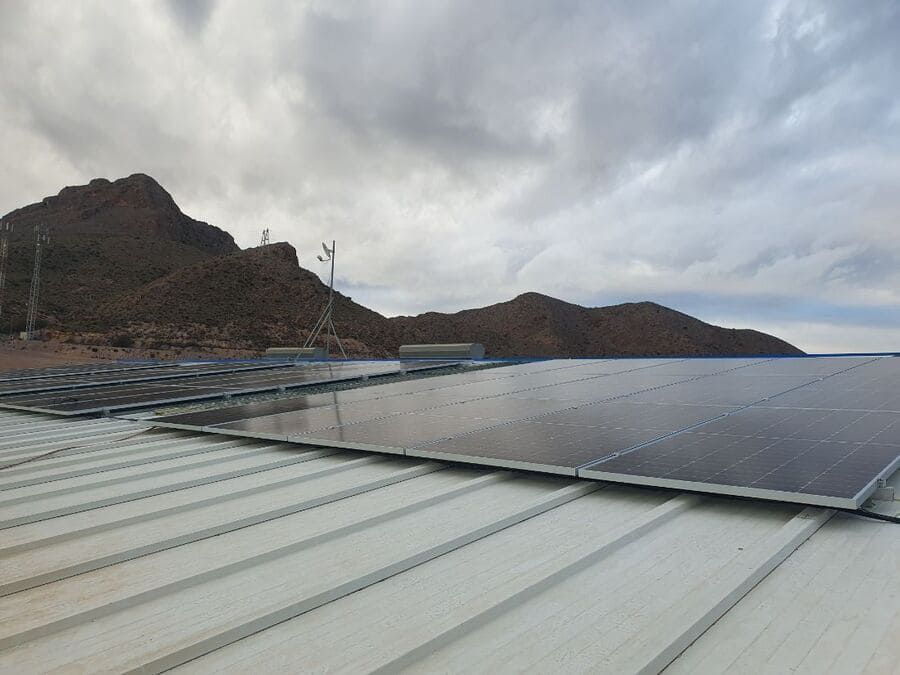 Un techo con muchos paneles solares y montañas al fondo.