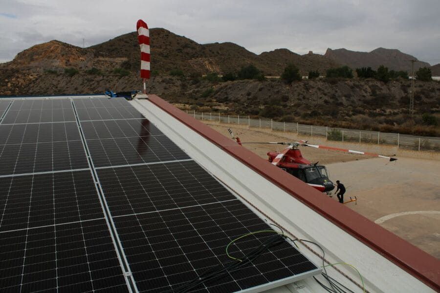 Un helicóptero está estacionado en el tejado de un edificio con paneles solares.