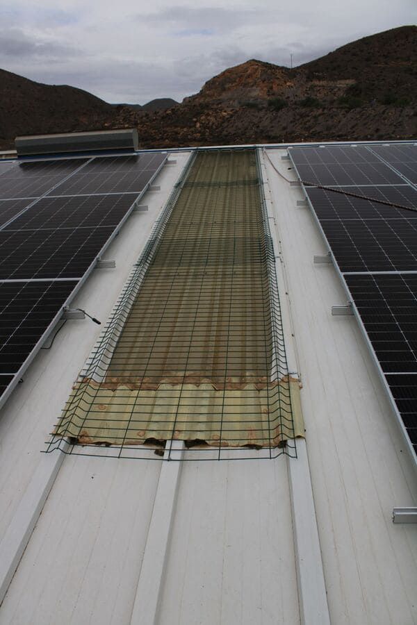 Una fila de paneles solares en un tejado con montañas al fondo.