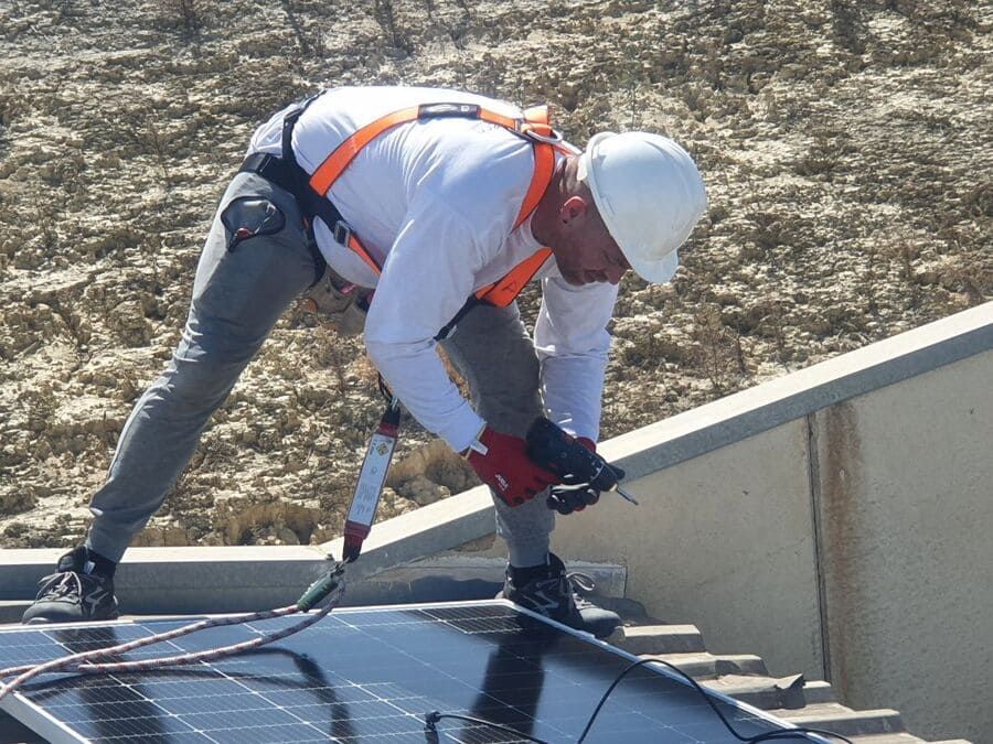 Un hombre que lleva un casco está trabajando en un panel solar.