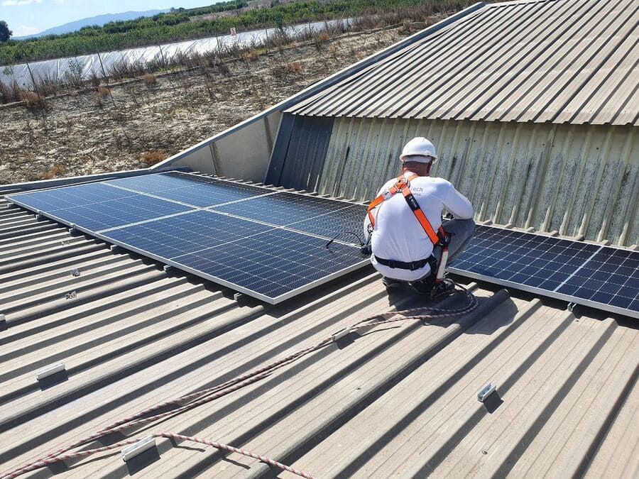 Un hombre está instalando paneles solares en el tejado de un edificio.