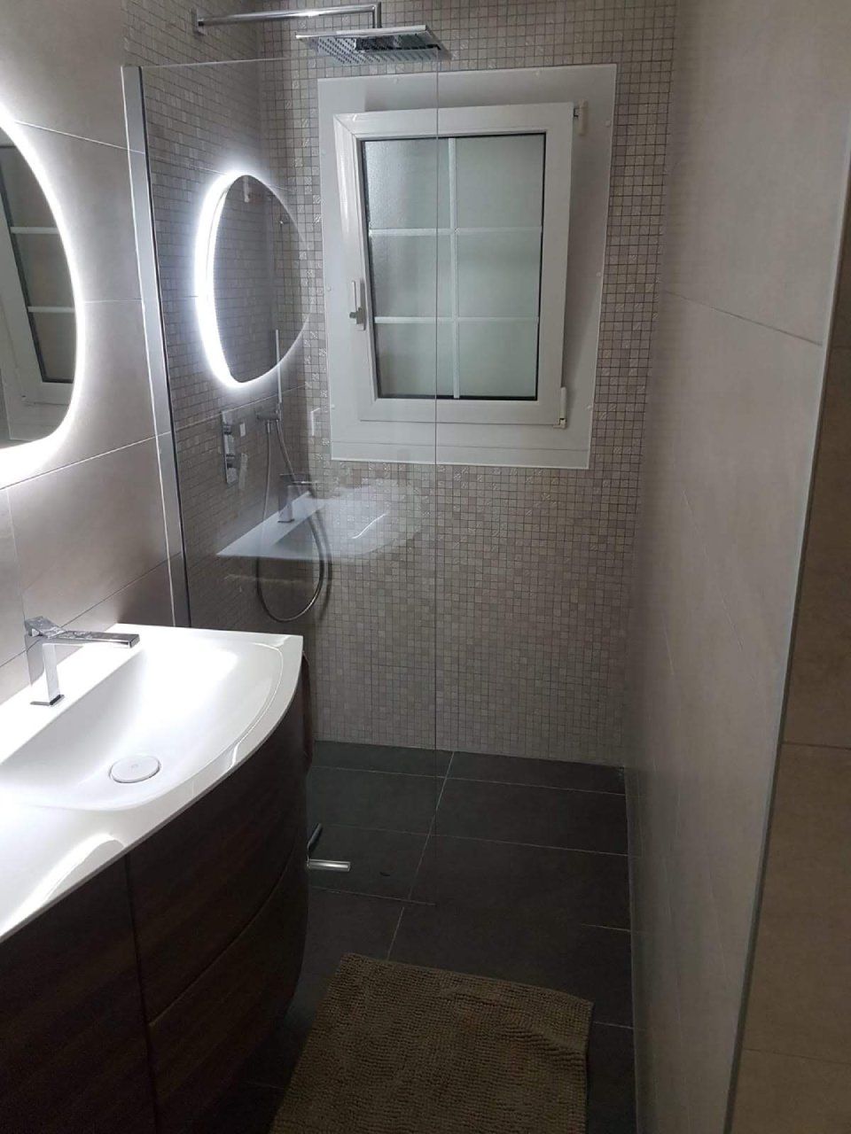 Une salle de bain avec lavabo, miroir et douche.