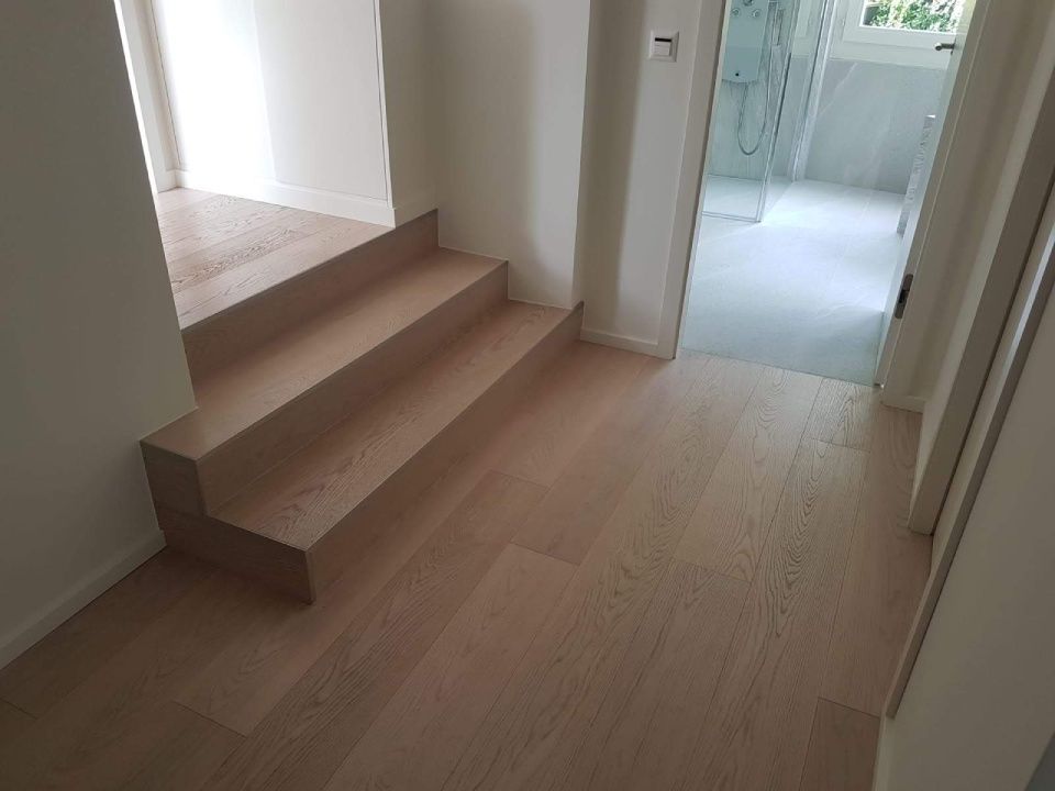 Un couloir avec un escalier en bois menant à une salle de bain.