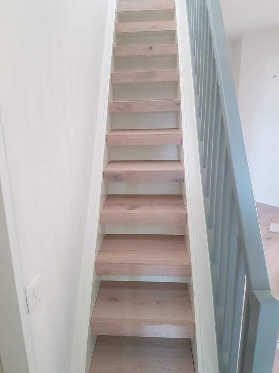 Un escalier en bois avec une rampe bleue dans une pièce.