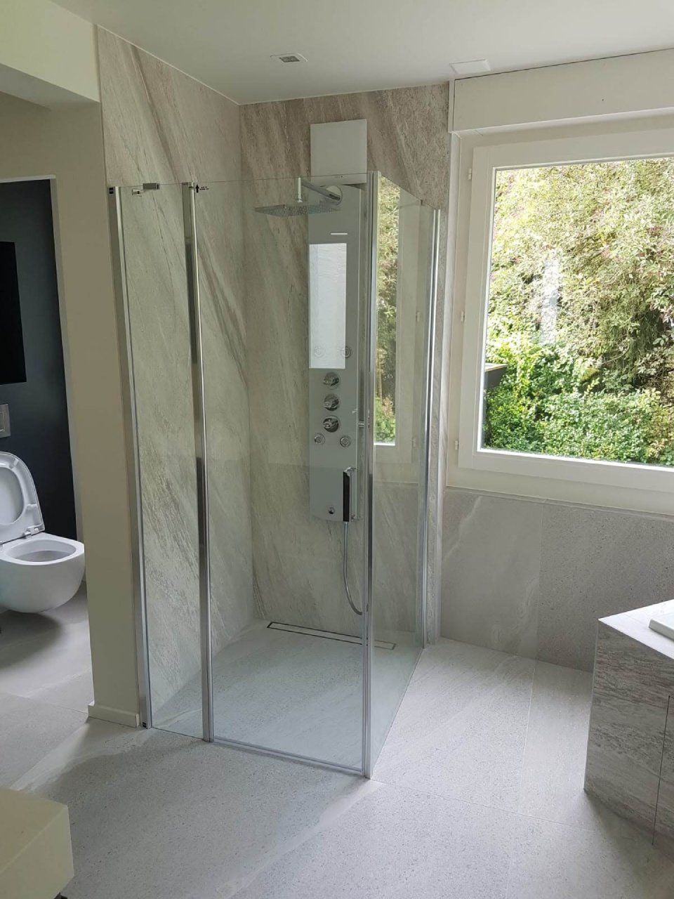 Une salle de bain avec douche à l'italienne, WC et fenêtre.