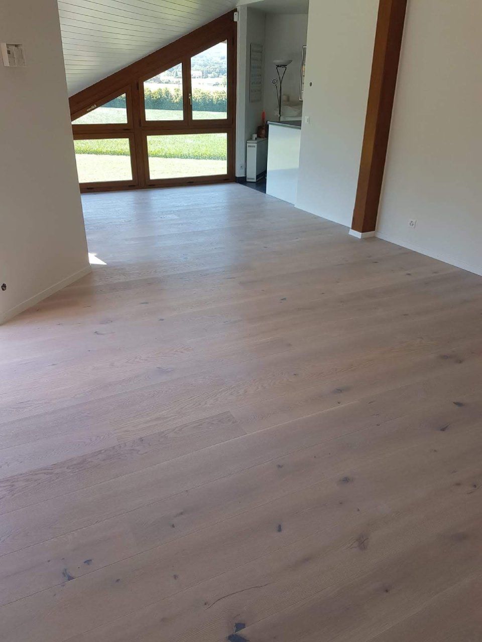 Une pièce vide avec un plancher en bois et une grande fenêtre.