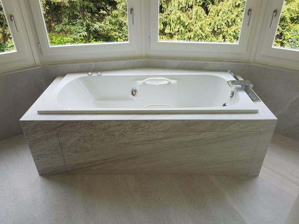 Une baignoire dans une salle de bain à côté d'une fenêtre