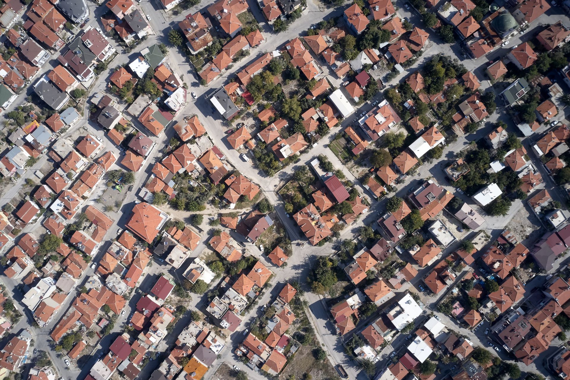 Vista aérea de un barrio densamente poblado con techos de tejas naranjas y algunos árboles.