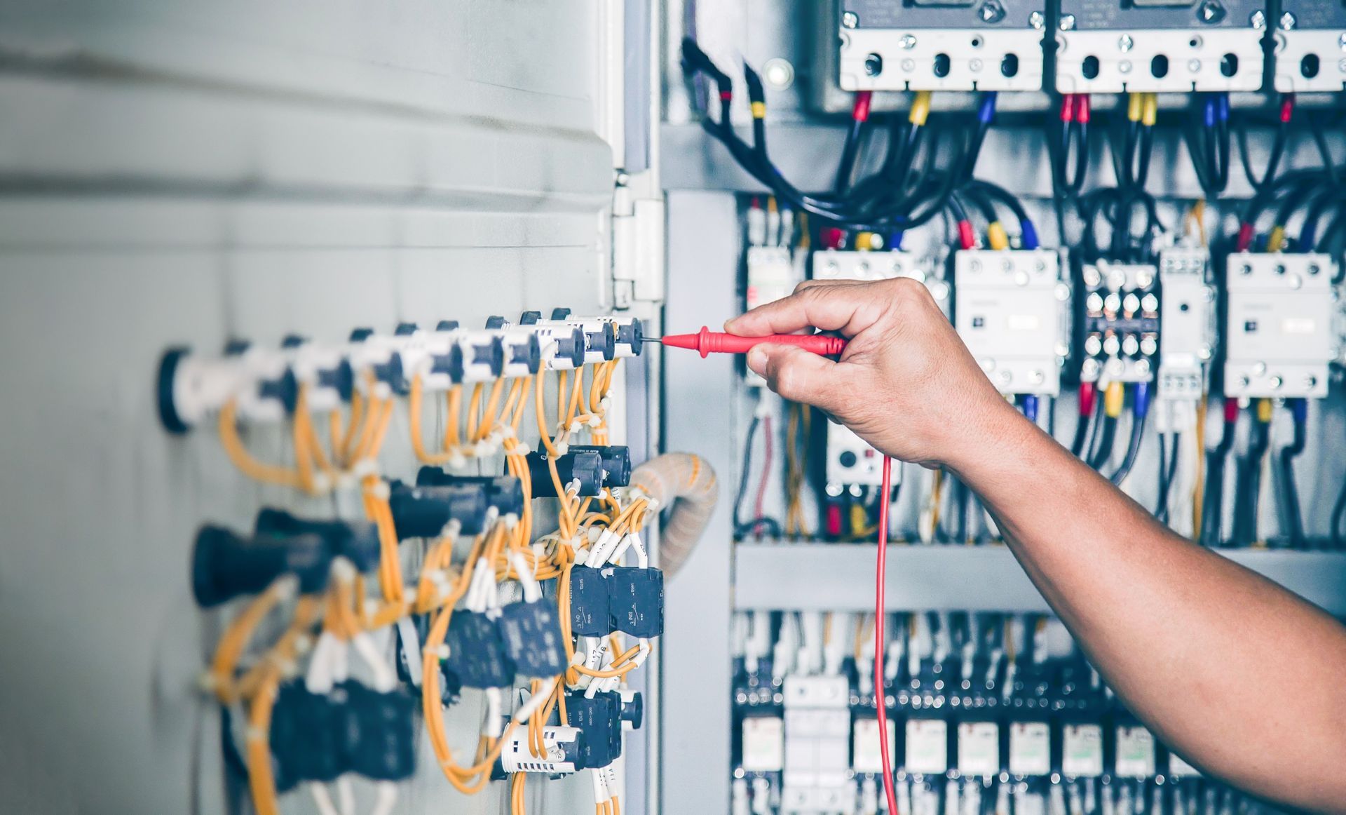 Electricista prueba cables en un panel eléctrico con un multímetro, centrándose en las conexiones