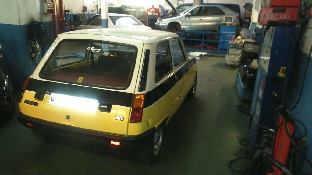 Renault 5 amarillo y negro en un taller de reparación de automóviles.