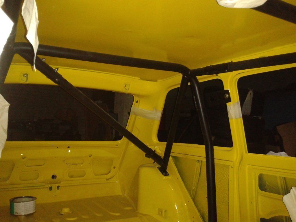 Dentro de un coche amarillo con jaula antivuelco negra.