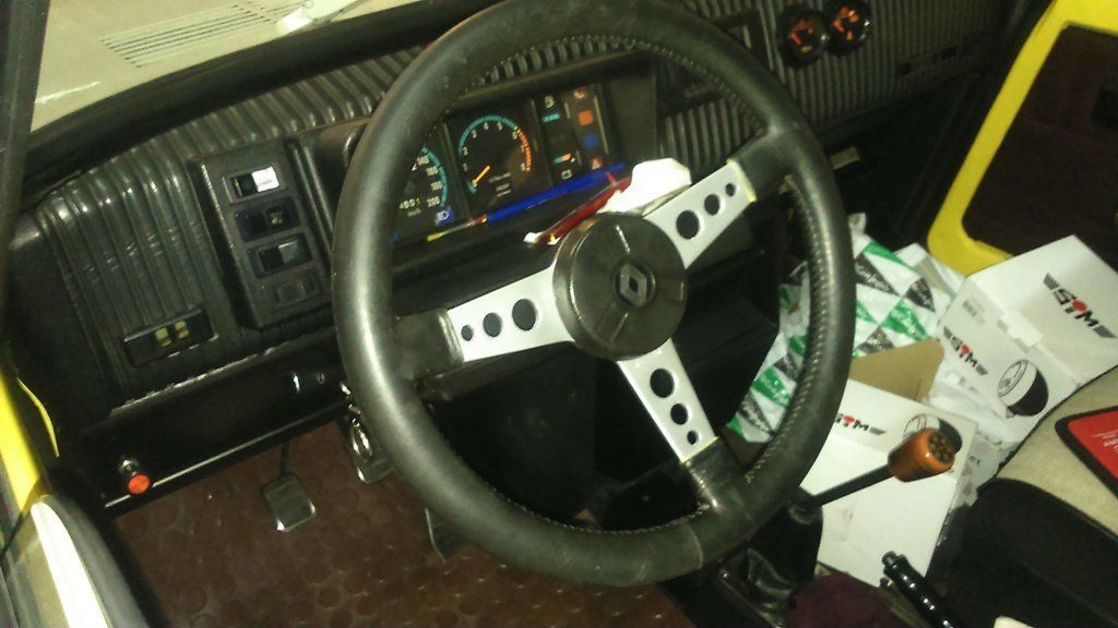 Vista interior del salpicadero de un coche clásico: volante negro, indicadores y detalles de madera.