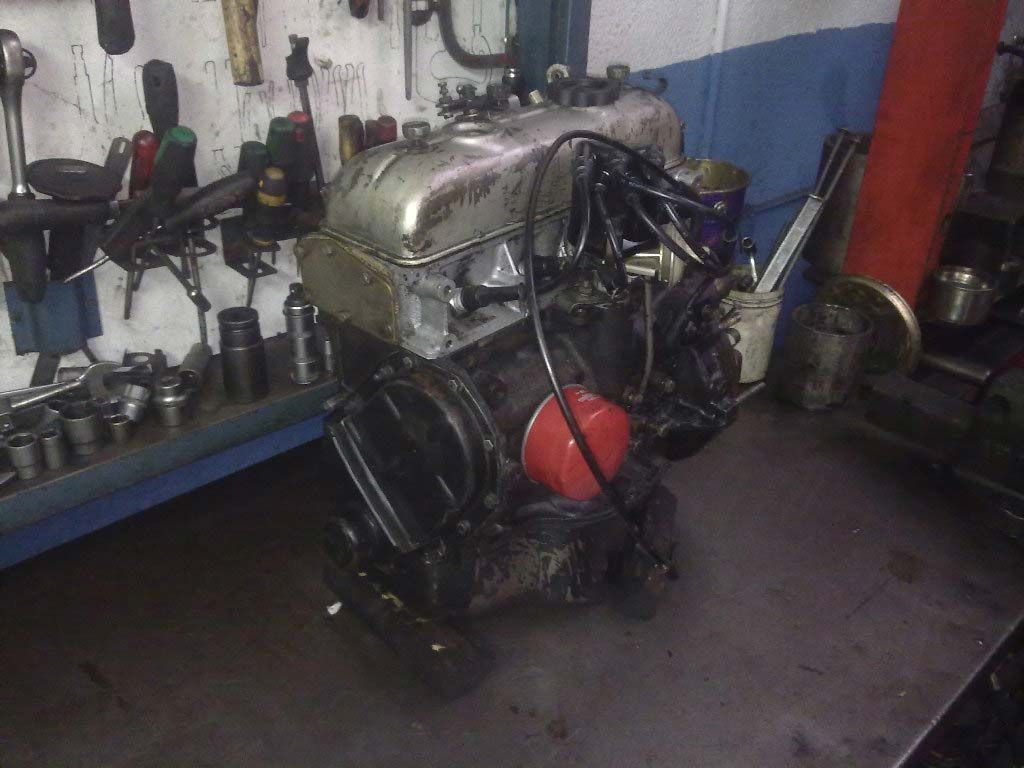 Un motor sobre un banco de trabajo en un taller mecánico, con herramientas al fondo.