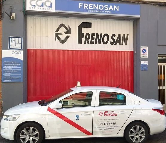 Taxi blanco estacionado frente al taller mecánico