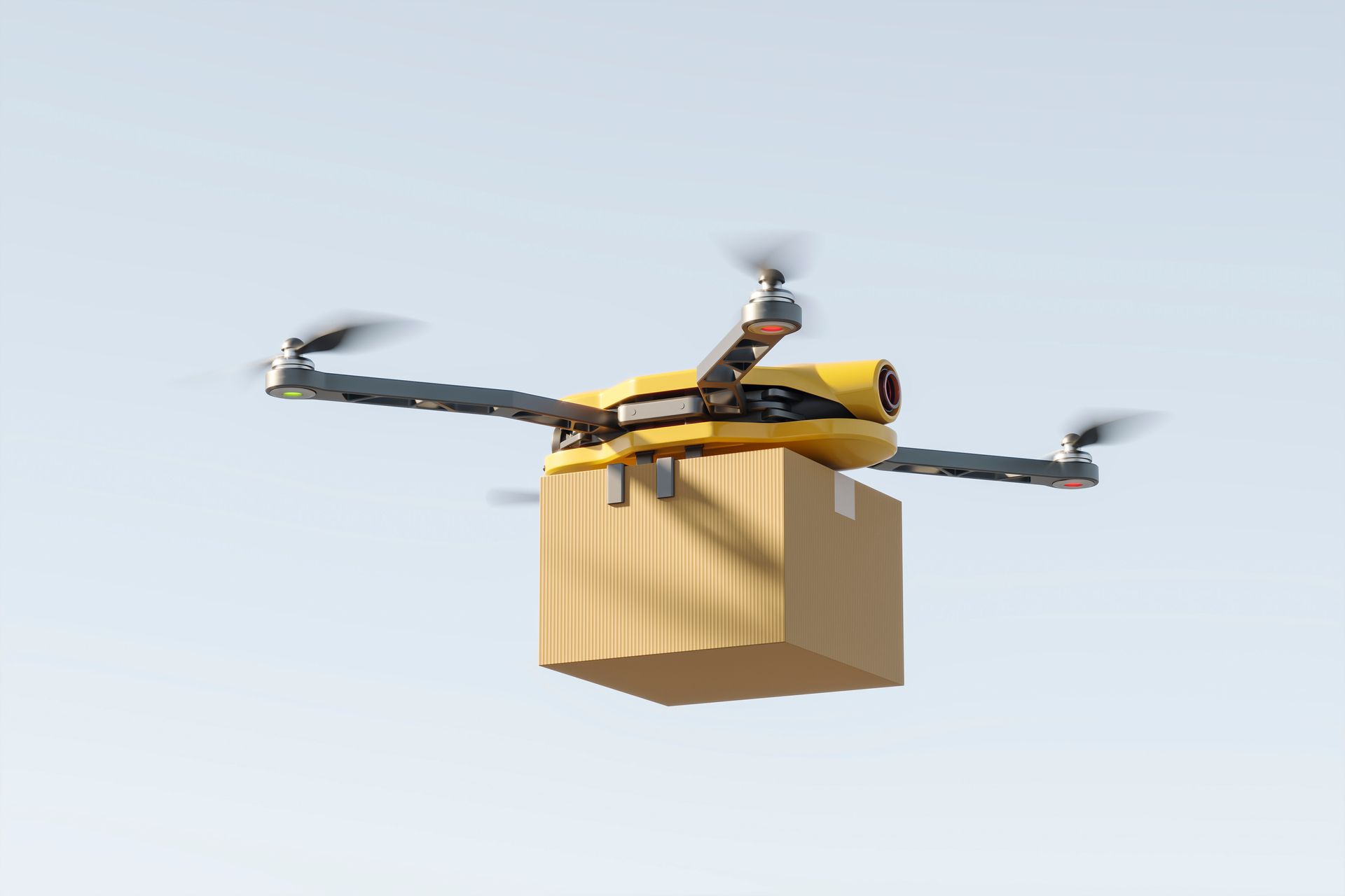 Drohne mit einem Karton an Bord, die vor blauem Himmel fliegt.