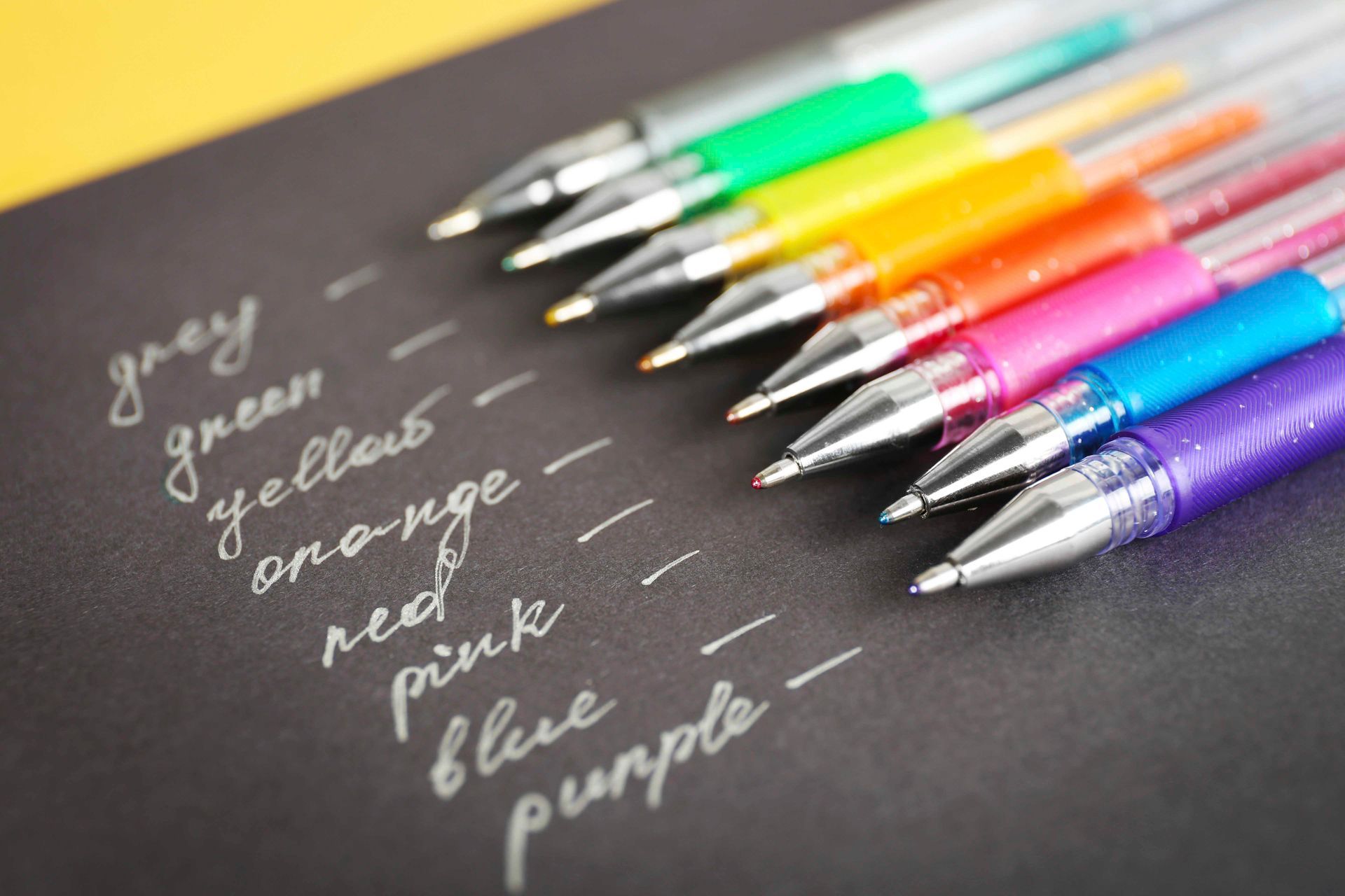 Reihen von bunten Gelstiften mit den entsprechenden, in Weiß geschriebenen Tintenfarbennamen.