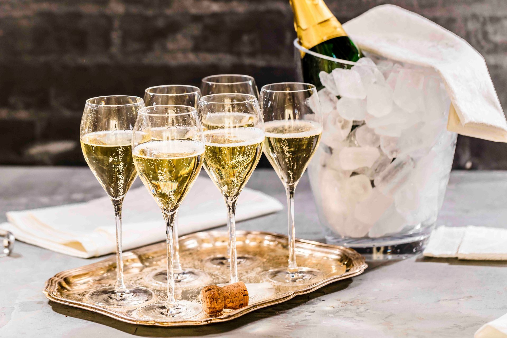 Champagnergläser gefüllt mit Sekt auf einem Tablett, Flasche im Eisbehälter.