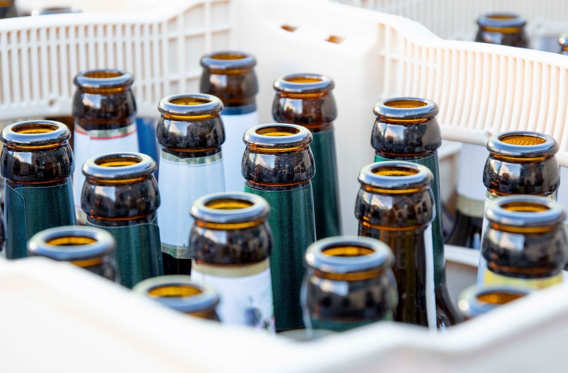 Leere braune und grüne Bierflaschen in einer weißen Kiste, Nahaufnahme.
